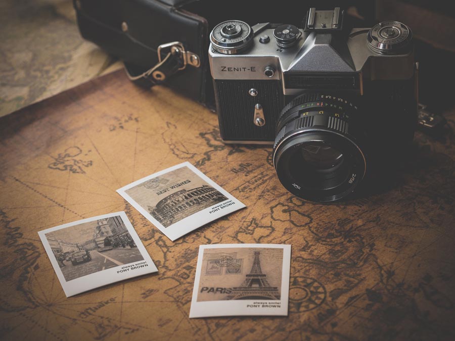 A camera and postcards on top of an old-fashioned map. Image by Dariusz Sankowski from Pixabay