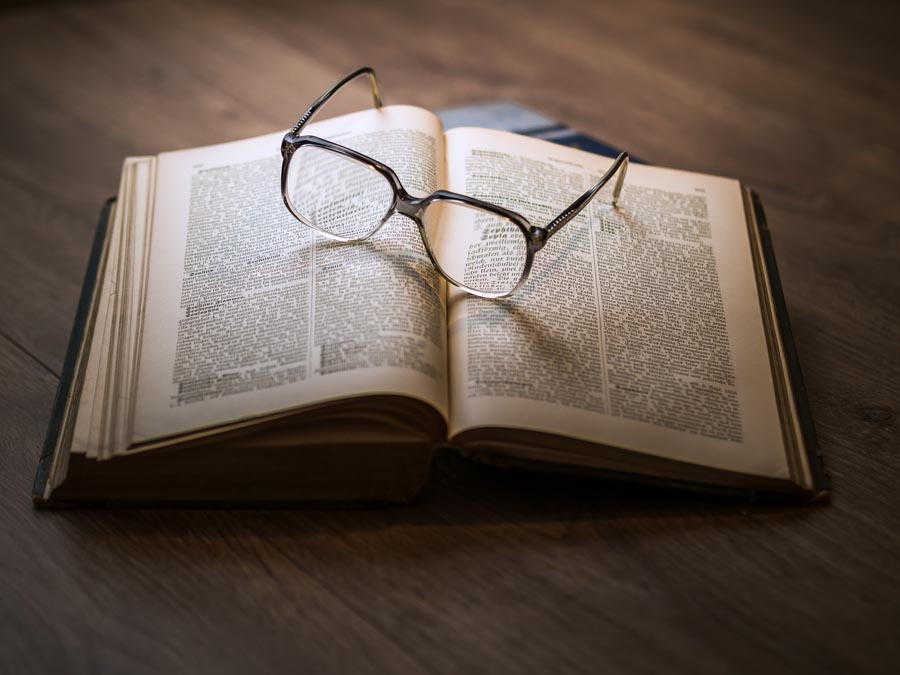 A picture of eyeglasses placed on an open book. Image by Dariusz Sankowski from Pixabay